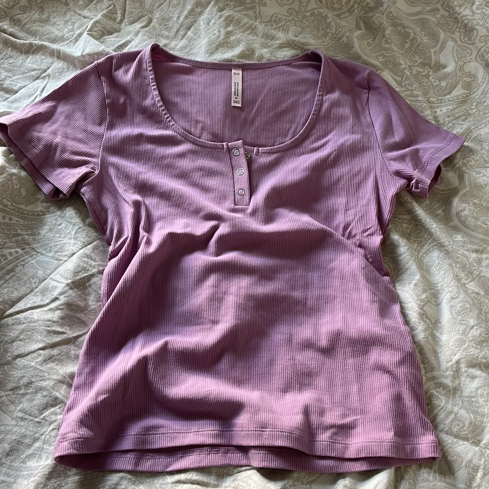 Säljer en lila ribbad topp med korta ärmar och knappar framtill. Jättemysig som pyjamaströja💕 endast använt en gång då det var tema dag i skolan haha💕 . Yläosat.