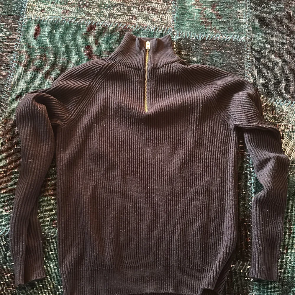 Säljer en stilren svart ribbad tröja från Jack & Jones med dragkedja i halsen. Perfekt för kyligare dagar med sin långa ärmar och bekväma passform. Ett måste i garderoben för en klassisk look.. Neuletakit & Villapaidat.