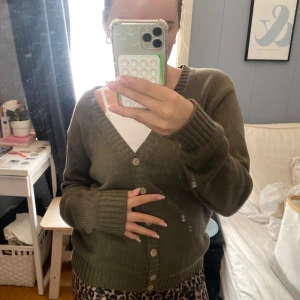 Olivgrön kofta från Brandy Melville - Säljer en olivgrön kofta från Brandy Melville. Den har en v-ringad design med knappar framtill och ribbade muddar vid ärmslut och nederkant. 