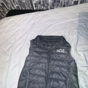 Grå dunväst från EA7 - Bra skick ett litet minimalt hål på insidan vid ryggen syns inte på bilderna men annars inga störe problem sitter bra och är använd såklart men priset är diskuterbart finns i Skåne . OBS Endast genom Swish!