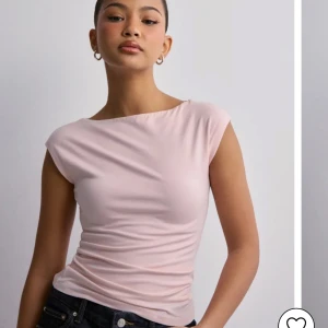Ljusrosa topp från Nelly💞 - Säljer en stilren ljusrosa topp med korta ärmar och en elegant, enkel design. Perfekt för en avslappnad men ändå chic look. Passar bra till jeans eller kjol💕