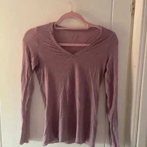 Lila långärmad tröja från Intimissimi - Säljer en mjuk och bekväm  tröja från Intimissimi. Tröjan har en v-ringad design och långa ärmar.