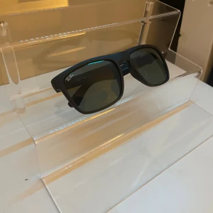 Svarta solglasögon från Ray-Ban - Snygga svarta solglasögon från Ray-Ban med klassisk design. De har en rektangulär form och mörka linser som ger ett stilrent intryck. Pris går att diskutera.