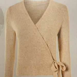 Omlottkofta - Säljer en stilren beige omlottkofta med knytband i midjan. Koftan har långa ärmar och en mjuk, bekväm passform. Perfekt för lager-på-lager. Oanvänd 