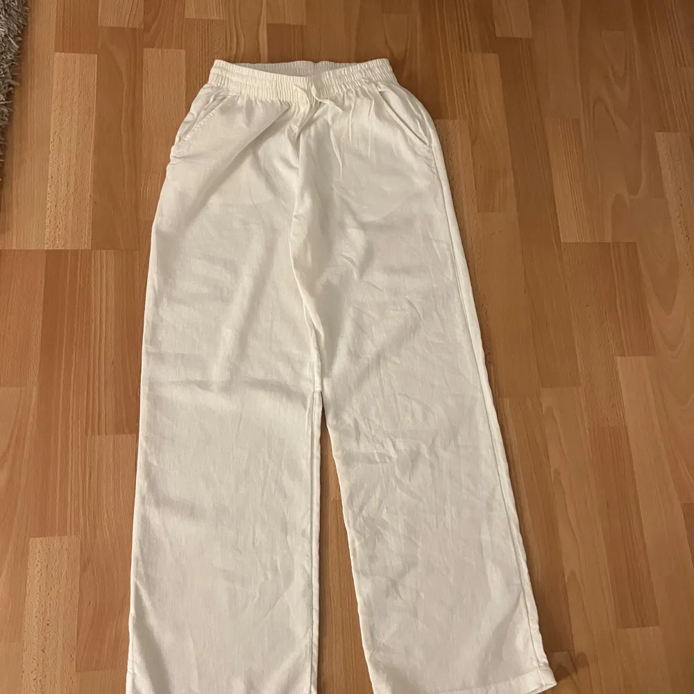 Snygga vita linnebyxor med resår i midjan för en bekväm passform. Byxorna har en rak och avslappnad stil, perfekt för en casual look.💕💕. Farkut & Housut.