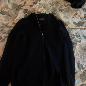Mörkblå kofta från Stenströms - Säljer en stilren mörkblå kofta från Stenströms med dragkedja framtill. Perfekt för både vardag och mer uppklädda tillfällen. Koftan har långa ärmar och en ribbad krage som ger en klassisk look. En personlig favorit som har blivit för liten. Inga tecken på defekter utan i topp skick!