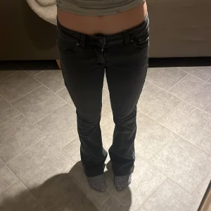 Svarta bootcut jeans - Snygga svarta bootcut jeans med låg midja. Perfekta för en avslappnad stil. De har en klassisk femficksdesign och stängs med dragkedja och knapp.