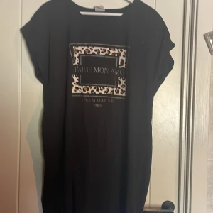 Svart nattlinne från Female Passion - Snygg svart nattlinne från Female Passion med leopardmönstrad detalj och texten 'Je t'aime mon amour'. Perfekt för en stilren look med en touch av djurmönster.