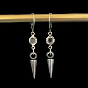 Silvriga örhängen med spetsig design - Snygga silvriga örhängen med en unik spetsig design. De har en rund detalj med en mörk sten och en hängande konformad spets. Perfekta för att ge en edgy touch till din stil.