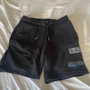 Svarta shorts från Hoodrich - Snygga svarta shorts från Hoodrich med snörning i midjan och coola tryckdetaljer. Perfekta för en avslappnad stil. De har en bekväm passform och är gjorda i ett mjukt material.