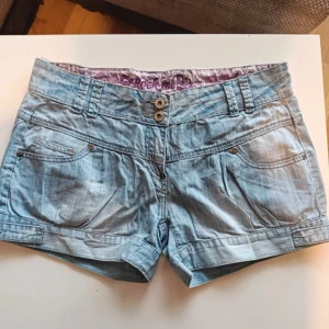 Ljusblå lågmidjade jeansshorts  - Ljusblå vintage lågmidjade jeansshorts i storlek M. De är i mycket bra skick, notera att det är ett litet hål under gylfen, inget som syns när shortsen sitter på. 