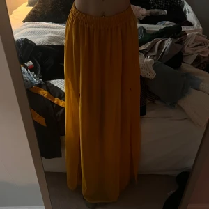 Gul långkjol med resårmidja och två slits  - Snygg gul långkjol med resår i midjan för en bekväm passform. Har slits på varsin sida. Kjolen har en luftig design som passar perfekt för varma dagar. Kommer passa en xs