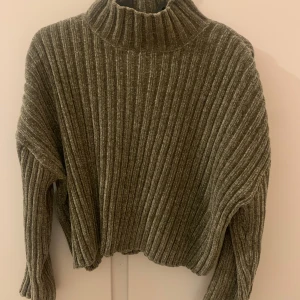 Stickad tröja - Säljer en mysig grön ribbad stickad tröja från FB Sister. Tröjan har en hög krage och långa ärmar, perfekt för kyliga dagar. Den har en avslappnad passform och är superbekväm att bära. Perfekt för höst och vinter! 🍂❄️