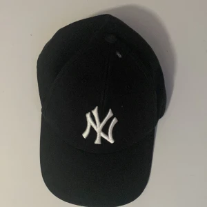 Svart keps med broderad logotyp - Snygg svart keps med en broderad vit logotyp framtill. Perfekt för en casual look och skydd mot solen. Justerbar passform för bekvämlighet.