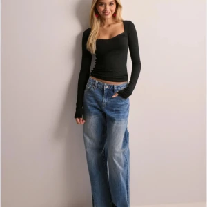 Svart långärmad topp - Snygg svart långärmad topp med en elegant fyrkantig urringning. Perfekt för en stilren look och kan matchas med både jeans och kjol.