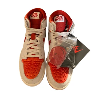 Nike Air Jordan 1 Zoom Air i röd och vit - Snygga Nike Air Jordan 1 Zoom Air sneakers i en fräsch kombination av rött och vitt. Skorna har en klassisk snörning och den ikoniska Air Jordan-loggan. Perfekta för dig som vill ha en stilren och sportig look. Btw dom är helt nya och har aldrig blivit använda 