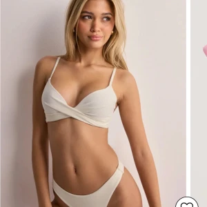 Vit bikini från Nelly - Snygg vit bikini från Nelly med omlott-design och smala axelband. Push up bikini. Överdelen är använd fåtal gånger medan nederdelen är helt ny. Båda två för 300kr. Överdelen slutsåld.