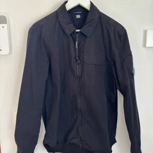 Svart jacka från C.P. Company - Säljer en svart jacka från C.P. Company. Skicket är bra utan några märken, hål eller trådar. Passar perfekt som vår och sommar jacka/overshirt. 