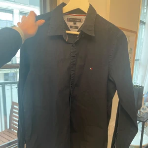 Skjorta från Tommy Hilfiger - Snygg skjorta från Tommy Hilfiger med klassisk krage och diskret logotyp på bröstet. Skjortan har långa ärmar och knappar framtill. Perfekt för en stilren look.