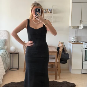 Svart långklänning - Elegant svart långklänning med smala axelband och en figurnära passform. 