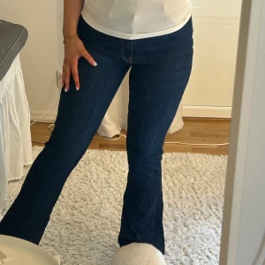 Mörkblå bootcut jeans - Snygga mörkblå bootcut jeans med hög midja. Perfekta för en stilren look. Jeansen har en klassisk design med fem fickor och en knappgylf. De är tillverkade i ett bekvämt denimtyg som ger en skön passform.