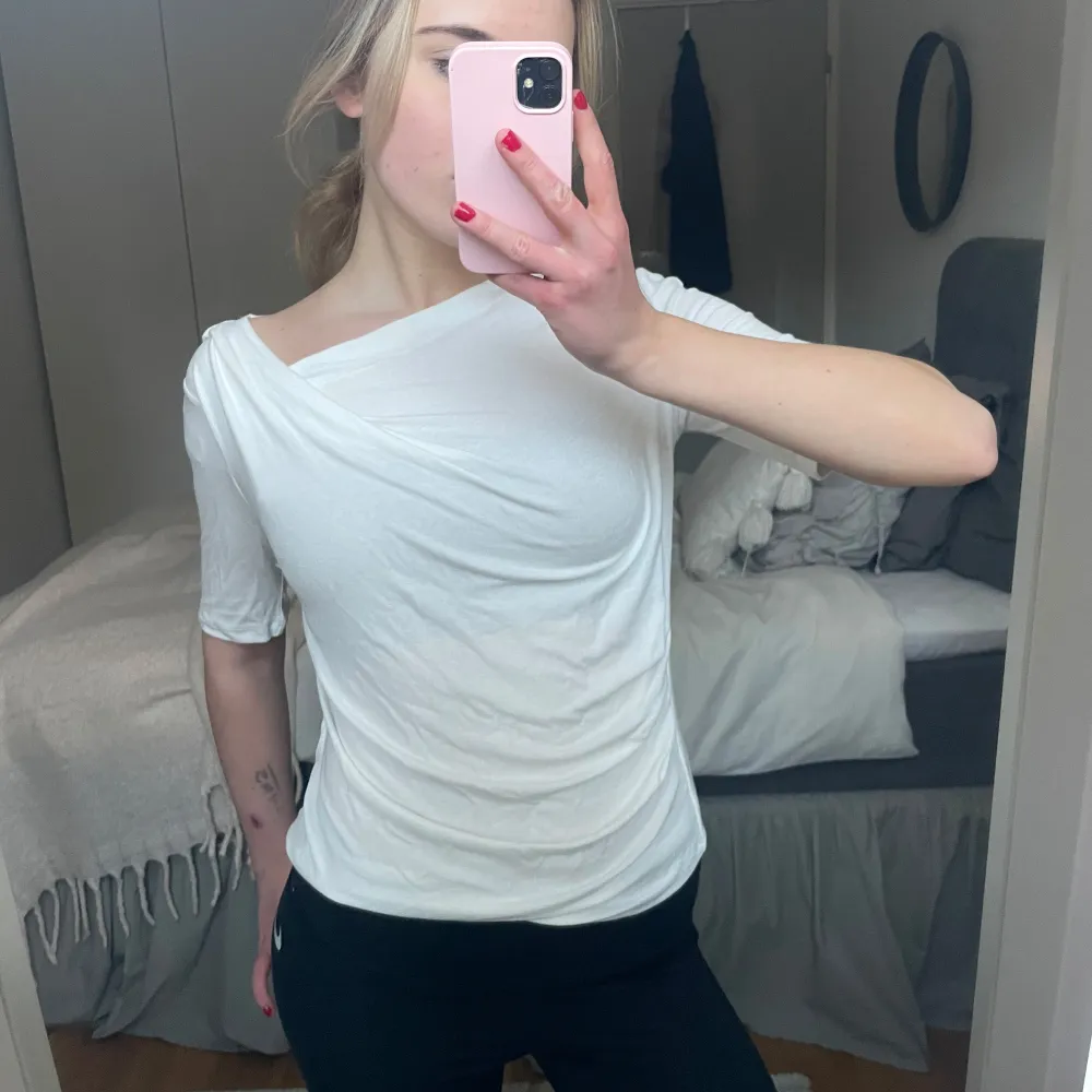 Säljer en stilren vit omlottopp med trekvartsärm. Toppen har en elegant drapering och en asymmetrisk halslinje som ger en unik look. Perfekt för både vardag och speciella tillfällen. Endast testad!. Yläosat.