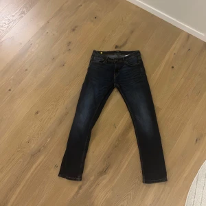 Mörkblå jeans från Smog - Säljer ett par mörkblå jeans från Smog med slim straight fit. De har klassisk femficksdesign och guldfärgade sömmar. Perfekta för en avslappnad stil.