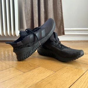 Svarta sneakers från Adidas - Snygga svarta sneakers från Adidas med en stilren design. Skorna har en stickad ovandel och en robust sula för extra komfort. Perfekta för både träning och vardag.