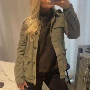 Olivgrön jacka med knappar - Snygg olivgrön jacka med knappar och flera fickor framtill. Perfekt för en avslappnad stil. Jackan har en normal passform och långa ärmar🤎