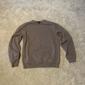 Grå tröja från H&M - Säljer en stilren grå tröja från H&M i loose fit. Tröjan har långa ärmar och är perfekt för en avslappnad look. Passar bra till både jeans och joggers.