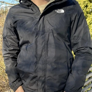 Svart jacka från North Face - Säljer en stilren svart jacka från North Face. Jackan har en praktisk huva och dragkedja framtill. Perfekt för blåsiga dagar och lätt att matcha med olika outfits.