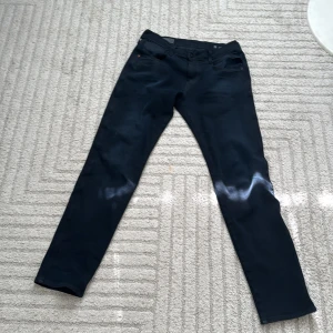 Replay Anbass Hyperflex svarta jeans - Svarta Replay Anbass Hyperflex jeans med slim passform och klassisk femficksdesign. Snygga detaljer med Replay-logga på fickan och stretchigt material som ger grym komfort. Perfekta för dig som gillar stilrena och moderna jeans.