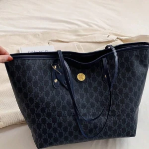 Grå och mörkblå shoppingväska MCM - Säljer två snygga shoppingväskor från MCM med klassiskt M-mönster över hela väskan. Ena är mörkblå och den andra är ljusgrå, båda har guldfärgade detaljer och långa handtag. Perfekt storlek för laptop, böcker och allt du behöver under dagen. Båda för 350