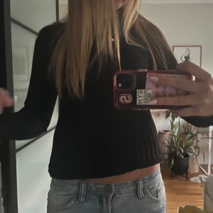 Svart ribbad stickad tröja - Tight stickad tröja med ribbat mönster, är lite uppvikt på bilden. Använd en gång, inga defekter. Strl M men sitter som S/XS