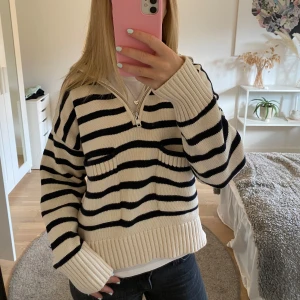 Randig skickad tröja - Supersöt randig stickad tröja från Zara. Den är créme vit med mörkblåa ränder och en krage i halsen. Dragkedjan går att justera själv. Använd ett fåtal gånger och i mycket bra skick! Hör av er vid frågor🩷🩷