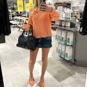 Orange stickad tröja med bred hals - Snygg orange stickad tröja med bred halsringning och långärmad modell. Tröjan har ett luftigt hålmönster och ribbade muddar vid ärmslut och nederkant. Perfekt att styla med jeans eller kjol för en chill look.