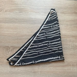 Bandana med kedjemönster - Snygg bandana i sidenliknande material med coolt kedjemönster. Perfekt att knyta runt halsen eller håret som en stilren accessoar med lite edge. Ca 50x50cm stor och aldrig använd. Vet ej märket.