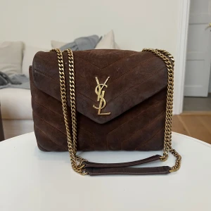 LouLou bag - Intressekoll på min fantastiska YSL Lou Lou bag i brun mocka. Väskan har vissa spår av användning, främst i form av fläckar på mocka. Den har aldrig rengjorts, men mocka är ett material som oftast går att fräscha upp relativt enkelt, vilket gör att väskan har stor potential att återställas till mycket fint skick. Perfekt till hösten🤎🤎 Bredd: 25cm Höjd: 17cm Djup: 9cm. Har självklart äkthetsbevis! Kan mötas upp i Stockholm 