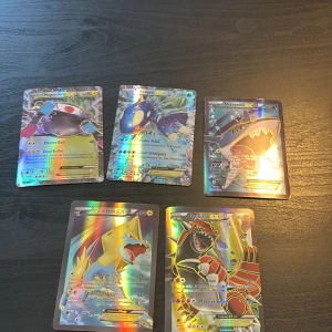 Pokémon EX Holo Collection - Samling med fem coola Pokémon EX-kort: Magnezone, Kyogre, Sharpedo, Manectric och Groudon. Alla kort är holo och har grymma attacker och effekter. Perfekt för dig som vill boosta din samling eller spela med extra stil! Färgstarka motiv och glansig finish gör dem till riktiga favoriter.