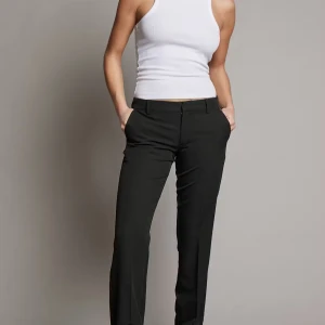 Svarta kostymbyxor från Bik Bok - Snygga svarta kostymbyxor från Bik Bok i klassisk rak modell med pressveck och fickor fram. Byxorna har normal passform och midwaist, perfekta till en clean och stilren look. Materialet är mjukt och har lite stretch för extra komfort.