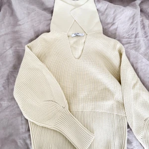 Beige stickad polotröja från NA-KD - Säljer en beige stickad polotröja från NA-KD i storlek S. Tröjan har bred ribbad struktur, långärmade ärmar med extra breda muddar och en snygg omlott-polo vid halsen. Perfekt för dig som gillar stilrena och mysiga plagg med modern touch. Aldrig använd