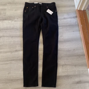 Svarta Lager 157 jeans herr - Säljer ett par svarta Lager 157 jeans med klassisk femficksdesign och smal passform. Jeansen har raka ben och är tillverkade i mjukt jeansmaterial med snygga kopparfärgade nitar. Perfekta för dig som gillar stilrena och tidlösa jeans.