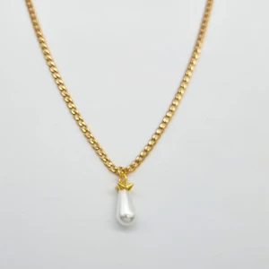 Guldhalsband med droppformad pärla - Stilrent halsband i guldtonad kedja med en droppformad vit pärla som hänge. Pärlan har en liten guldfärgad detalj upptill som ger ett unikt och trendigt uttryck. Perfekt accessoar för att lyfta din look med en elegant touch.