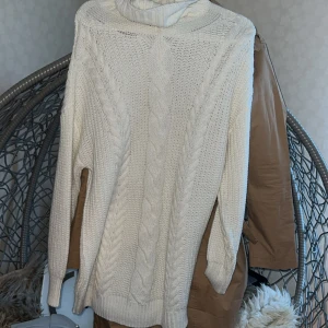 Vit polotröja med kabelstickning - Säljer en vit polotröja med grov kabelstickning och ribbade muddar. Tröjan har lång ärm och hög krage som ger extra mysfaktor. Perfekt för kyliga dagar och passar dig som gillar klassisk stil med en modern twist.