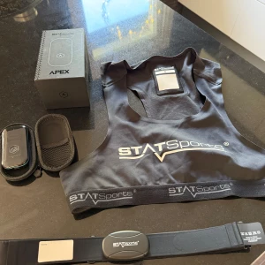 Svart träningsväst från STATSports - Säljer en svart träningsväst från STATSports, perfekt för sport och träning. Västen har en sportig design med logga framtill och elastiskt band nedtill. Materialet är lätt och syntetiskt, med en ficka på ryggen för GPS-enhet. Passar dig som vill mäta prestationer.