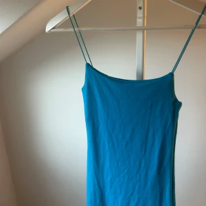 Blå Zara klänning med smala band - Snygg blå klänning med smala axelband och rak passform. Klänningen är ärmlös och har en enkel, stilren design som känns fräsch och modern. Perfekt för dig som gillar minimalistisk stil och vill ha något lätt och bekvämt.