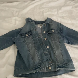 Blå jeansjacka från LAB Industries - Snygg klassisk blå jeansjacka från LAB Industries med silverfärgade knappar och två bröstfickor. Jackan har en rak passform, krage och långa ärmar. Perfekt att slänga över en hoodie eller t-shirt för en chill look.