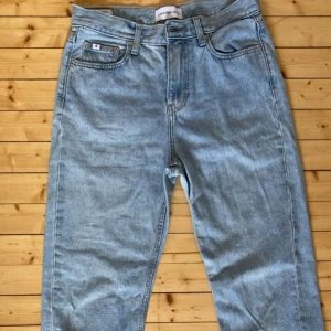 Ljusblå jeans från Calvin Klein - Säljer ett par ljusblå jeans från Calvin Klein högmidjat med rak passform. Jeansen har en  skråma på vänster ben men i övrigt i bra skick