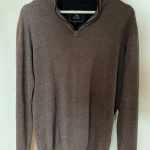 Brun stickad tröja med half zip - Snygg brun stickad tröja från Carl William i storlek M mycket bra skick. Tröjan har en half/quarter zip, perfekt för dig som gillar klassisk stil med en modern touch.