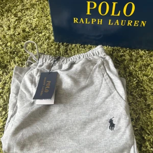 Grå shorts från Polo Ralph Lauren - Polo Ralph Lauren Shorts – Storlek L – 499 kr  Stilrena och bekväma grå shorts från Polo Ralph Lauren – perfekta för både vardag och avslappnat häng. ✔️ Ikoniska Polo-loggan broderad framtill ✔️ Mjuk och skön bomullsmix ✔️ Resår i midjan med snörning för flexibel passform ✔️ Storlek: L  Nypris betydligt högre – nu kan du fynda dessa exklusiva shorts för endast 499 kr!